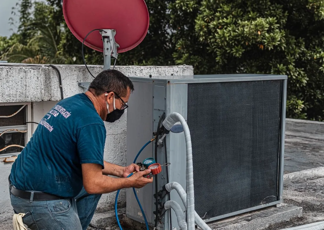 Técnico revisando um ar-condicionado split durante manutenção preventiva